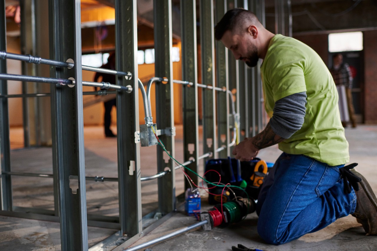 White electrician kneeled in front of receptacle box working