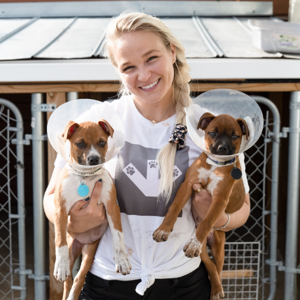 Girl smiling holding two puppies