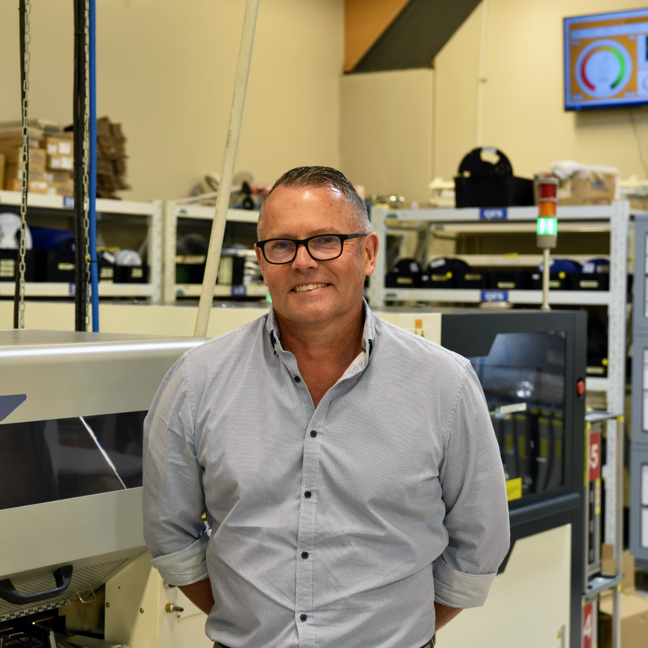 White man standing in factory smiling